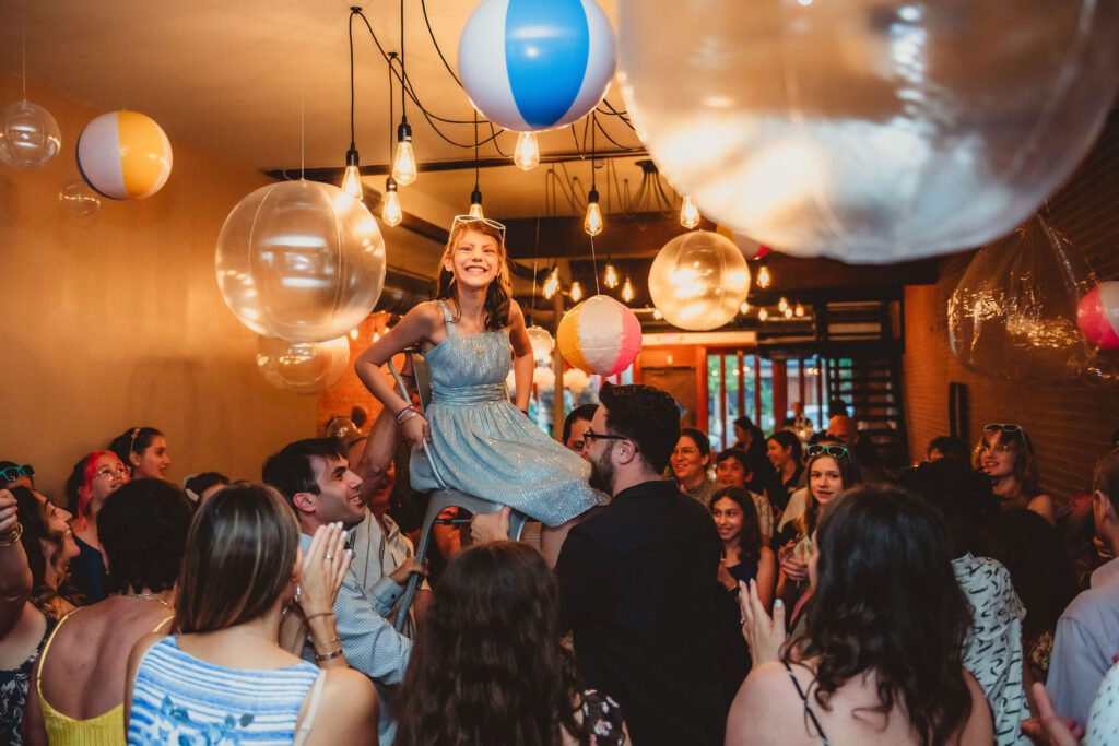 Guests lifting Bat Mitzvah girl during the Hora dance at a Bat Mitzvah celebration